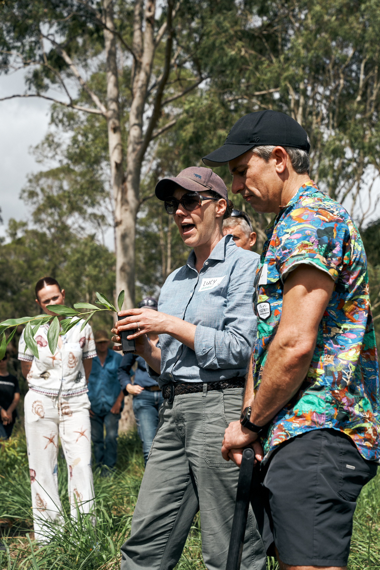 Reforest ecologist Lucy holding a seedling and explaining the planting to Challenger guests